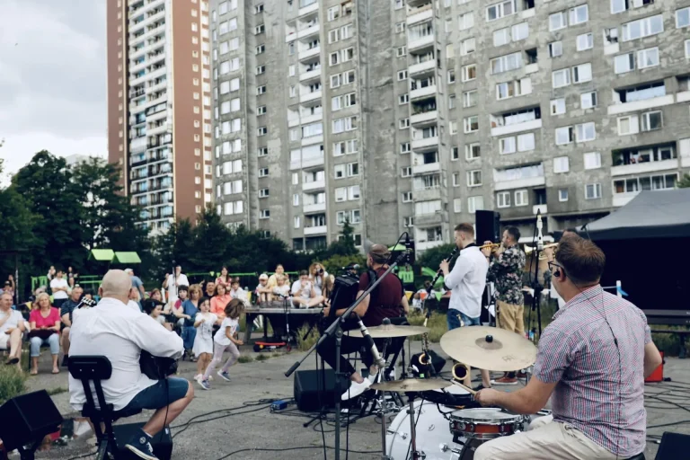 Perkusista Propabanda grający na plenerowej scenie, w tle publiczność i bloki mieszkalne