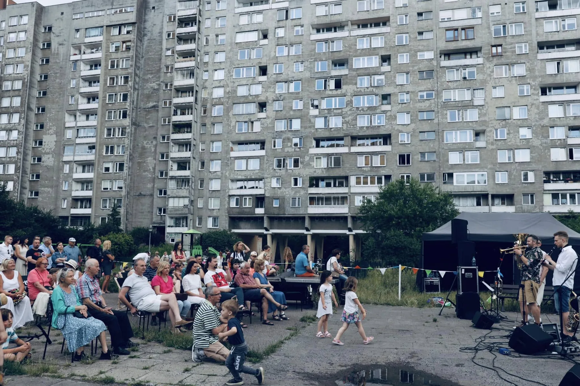Publiczność siedząca na krzesłach podczas plenerowego koncertu Propabanda na osiedlu